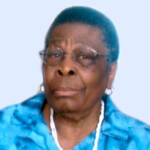 Elderly woman in blue shirt and white necklace.