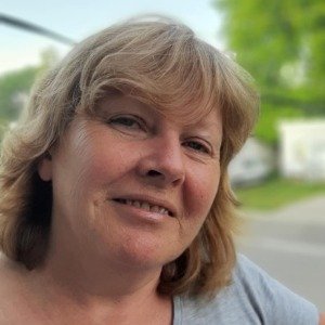 Smiling woman outdoors with green background.