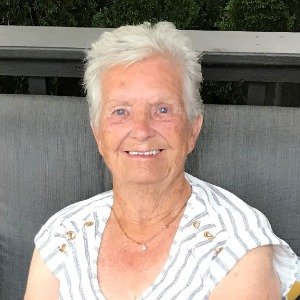 Smiling elderly woman sitting on a patio chair.