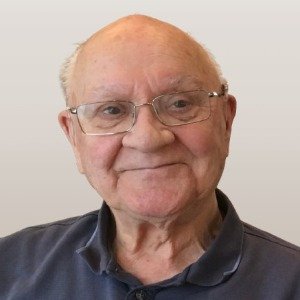 Smiling elderly man wearing glasses and a polo shirt.