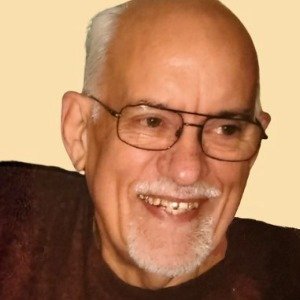 Smiling elderly man with glasses and beard.