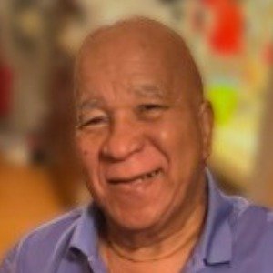 Smiling elderly man in casual shirt indoors.