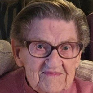 Elderly person wearing glasses, smiling slightly.