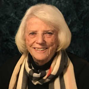 Smiling person with white hair and striped scarf.