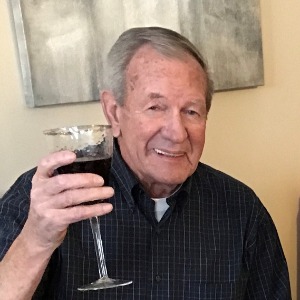Man toasting with glass of red wine indoors.