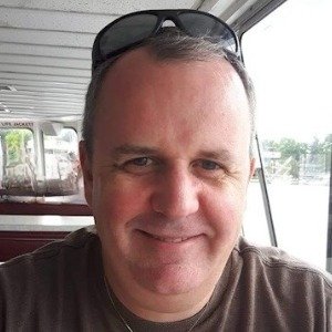 Smiling person indoors with sunglasses on head.