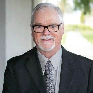Older man in suit and glasses smiling