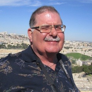 Smiling person with glasses outdoors.