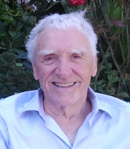 Smiling elderly man in garden setting.