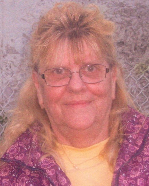Woman with glasses and patterned jacket smiling