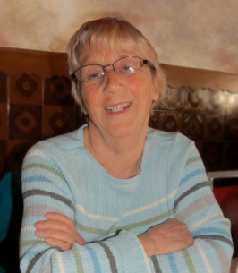 Smiling person with glasses and striped sweater.