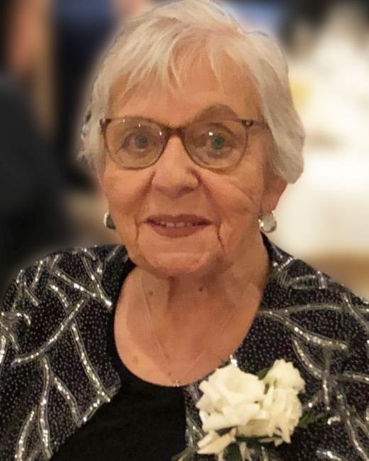Elderly woman wearing glasses and floral corsage.
