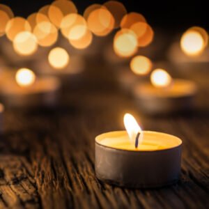 Glowing tea light candles on wooden surface