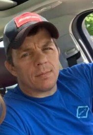 Man wearing blue shirt and cap in car
