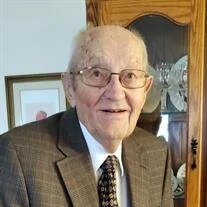Elderly man in a suit smiling indoors.