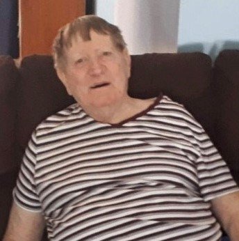 Elderly person sitting on a couch, wearing stripes.