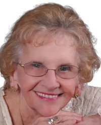 Smiling elderly woman with glasses and gray hair.