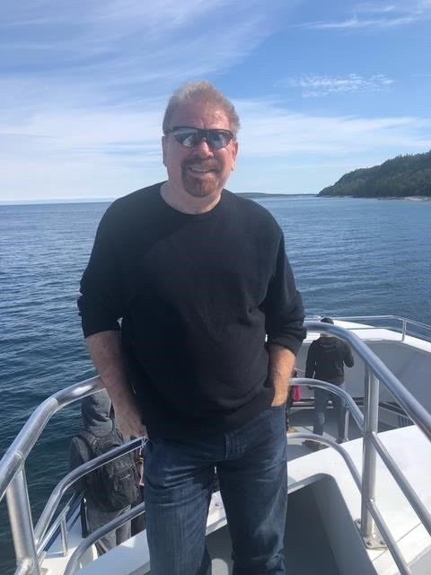 Man smiling on a boat in ocean scenery.
