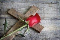 Wooden cross with red rose on it