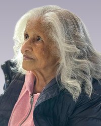 Elderly woman with long gray hair and jacket.