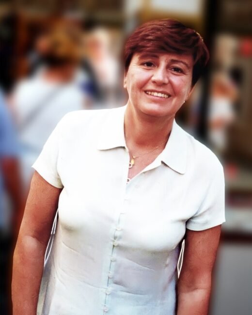 Smiling person in white shirt against blurred background.