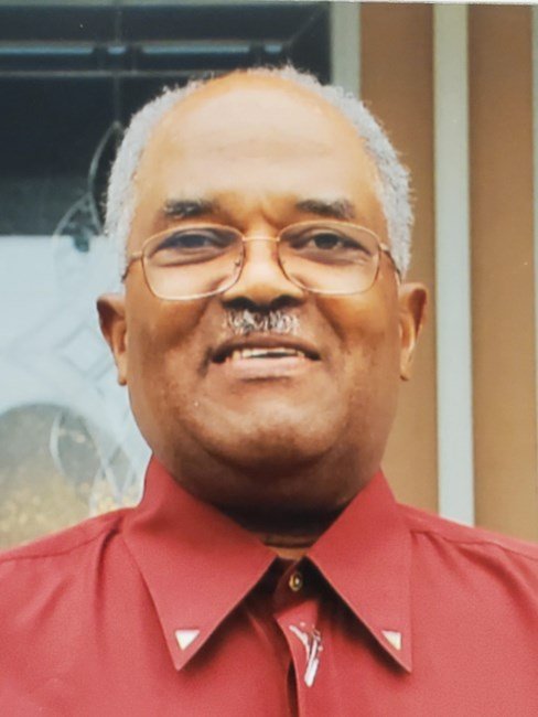 Smiling man wearing a red shirt and glasses.