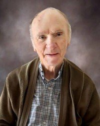 Elderly man in sweater and plaid shirt portrait.