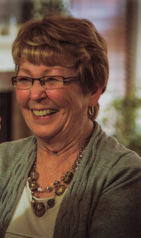 Smiling woman wearing glasses and jewelry.