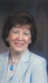 Woman in blue suit smiling in portrait photo.