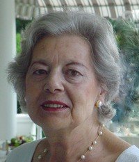 Elderly woman smiling, wearing pearls.