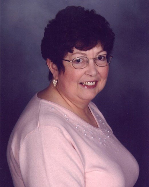 Smiling woman in glasses with pink top.