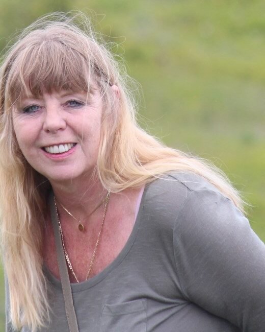 Smiling woman outdoors with green background.