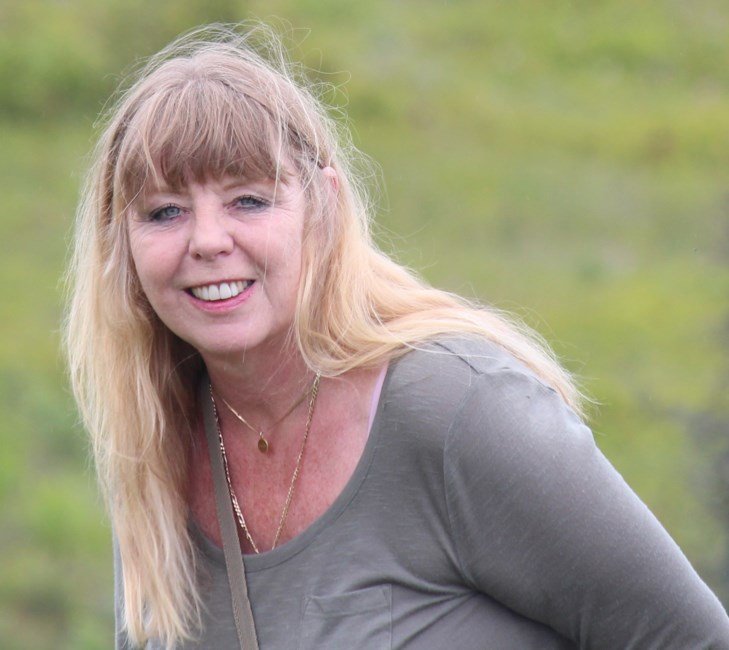 Smiling woman outdoors with green background.