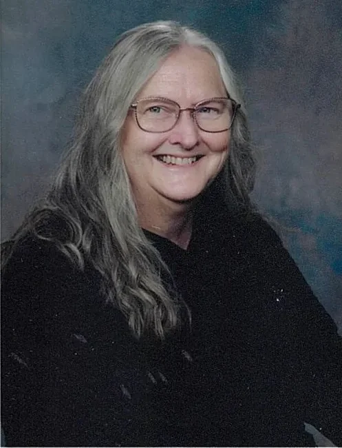 Smiling woman with long gray hair and glasses