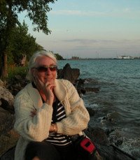 Person sitting by a scenic lakeside at sunset.