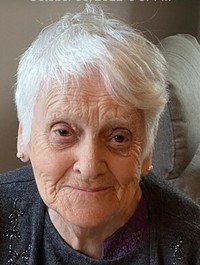 Elderly woman with white hair smiling gently.