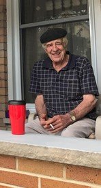 Elderly man sitting outside with coffee and cigarette.