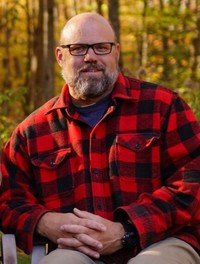 Man in plaid shirt sitting outdoors in autumn
