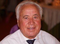 Smiling elderly man in white shirt and tie.