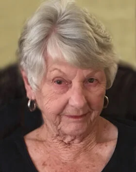 Elderly woman with short white hair and earrings.
