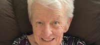 Smiling elderly woman sitting on a chair.