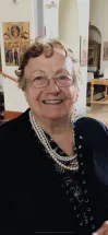 Smiling woman with pearls in elegant setting.
