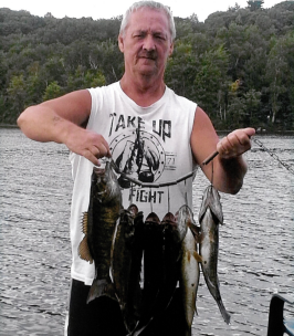 Man holding fishing line with fish at lake