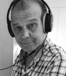 Man wearing headphones and checkered shirt, looking ahead.