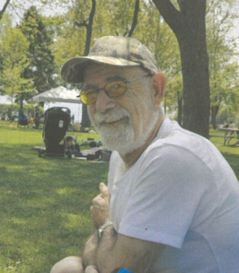 Man in park wearing glasses and a cap.