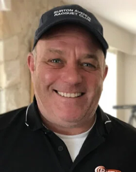 Smiling man wearing cap and polo shirt indoors.
