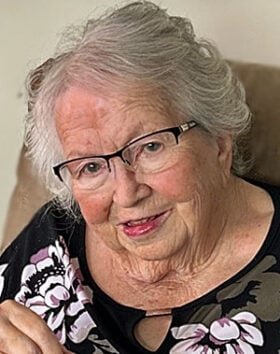 Smiling elderly woman with glasses and floral shirt