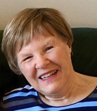 Smiling person with short hair wearing striped shirt.