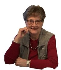 Smiling woman sitting with hand on chin.