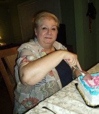 Person cutting colorful cake at table.